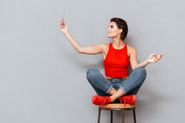 Smiling young woman making selfie photo on smartphone - Foto, afbeelding