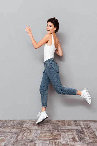 Cheerful pretty girl jumping over gray background - Foto, immagini