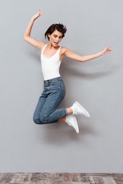 Laughing young brunette girl jumping - Fotografie, Obrázek