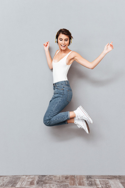 Woman listening music with headphones and jumping in the air - Photo, image