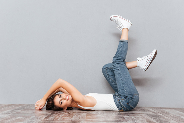 Smiling attractive woman lying on the floor with raised legs - Photo, Image