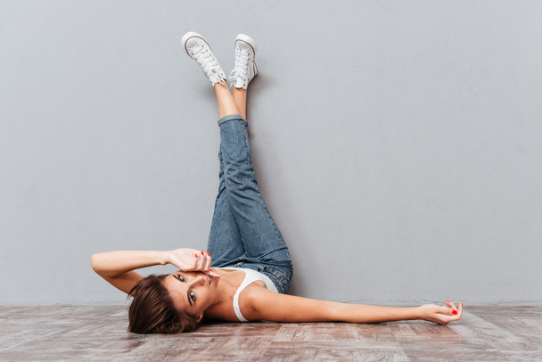 Sorridente bella donna sdraiata sul pavimento con le gambe sollevate
 - Foto, immagini