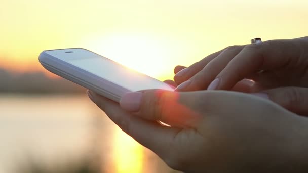 Крупним планом жіноча рука за допомогою смартфона на заході сонця
 - Кадри, відео