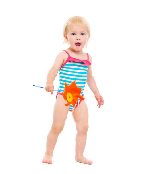 Surprised baby girl in swimsuit with pinwheel - Photo, Image