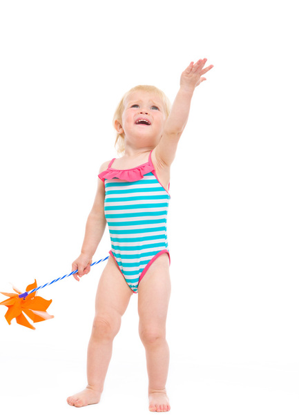 Happy baby in swimsuit with pinwheel pointing up - Zdjęcie, obraz