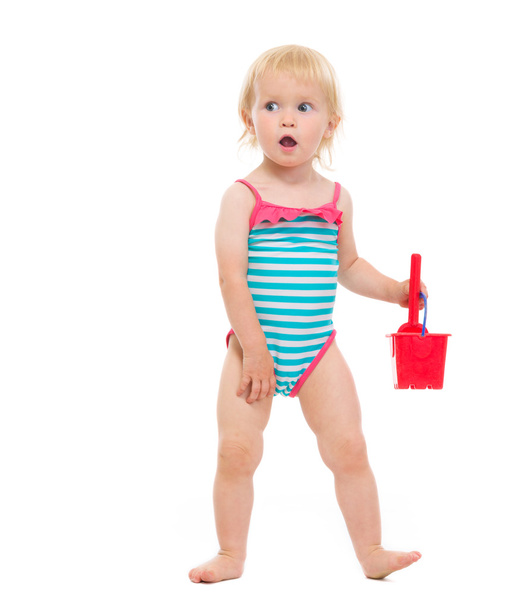 Surprised baby in swimsuit playing with bucket and shovel - Photo, Image