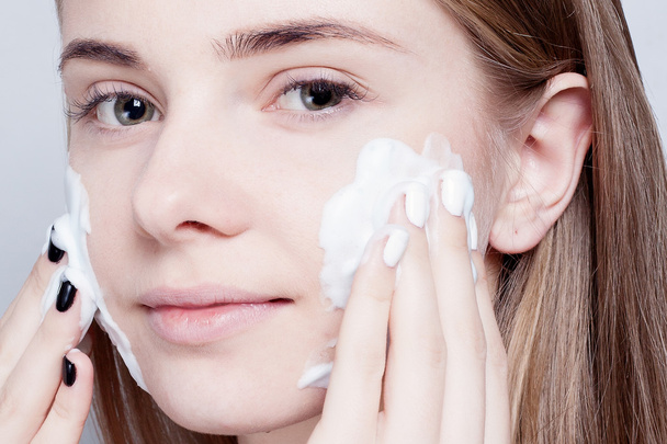 Close-up woman clears skin foam on gray background - Zdjęcie, obraz