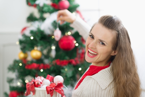 Happy young woman decorating Christmas tree - Valokuva, kuva