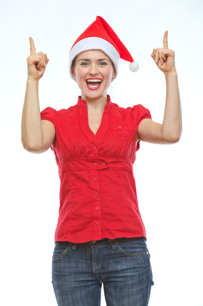 Smiling young woman in Christmas hat pointing up - Fotografie, Obrázek