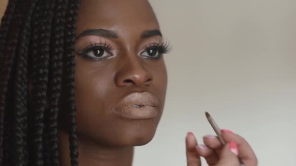 Makeup artist makes a beautiful makeup for beautiful african american girl - Filmmaterial, Video