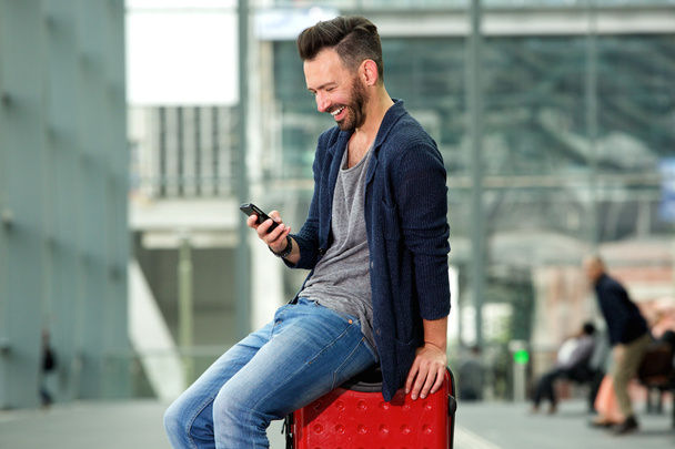 Sonriente viajero de mediana edad sentado en la maleta
 - Foto, Imagen