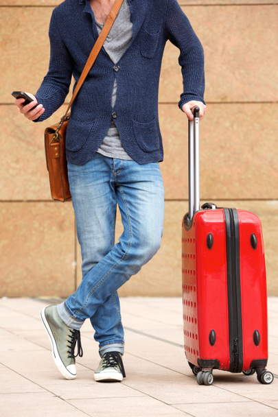 Man standing on sidewalk with suitcase - Photo, Image