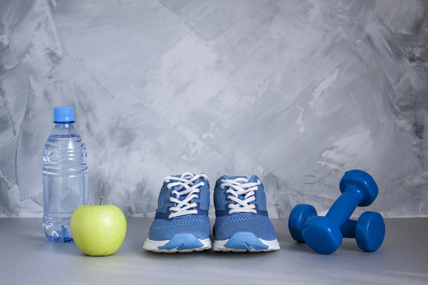 スポーツの靴, ダンベル, アップル, 灰色の背景上に水のボトル - 写真・画像