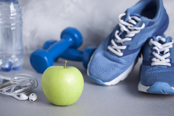 Sapatos esportivos, halteres, fones de ouvido, maçã, garrafa de água
 - Foto, Imagem
