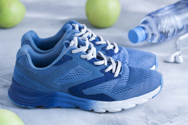Zapatos deportivos, botella de agua, manzanas sobre fondo de hormigón gris
 - Foto, Imagen