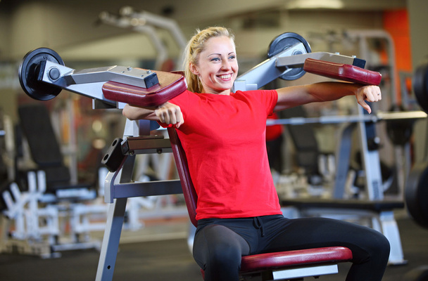 Cheerful young woman working out on exercise machine - Fotografie, Obrázek