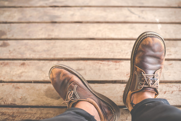 Top view of Male feet in old leather shoes on wood - 写真・画像