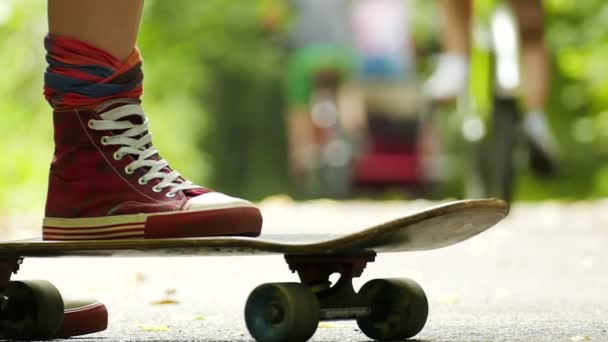 Female leg, skateboard and bicycles in  distance. Slow motion - Footage, Video