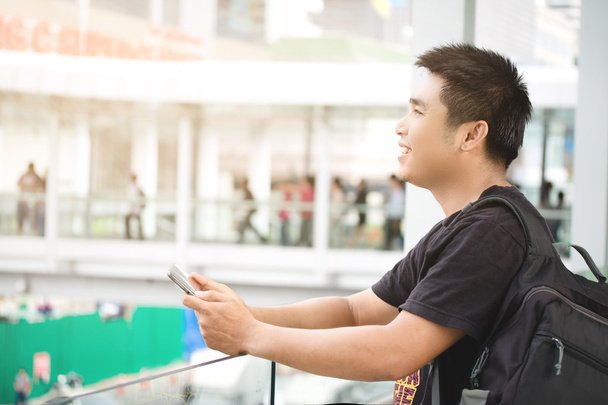 Έναν άνδρα να στέκεται στο πεζοδρόμιο σερφάρετε στο Internet και στο smart ph - Φωτογραφία, εικόνα