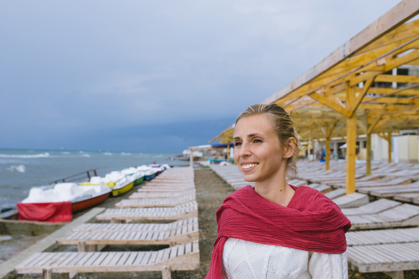 young woman wrapped up in a red woven scarf by the sea - Foto, afbeelding