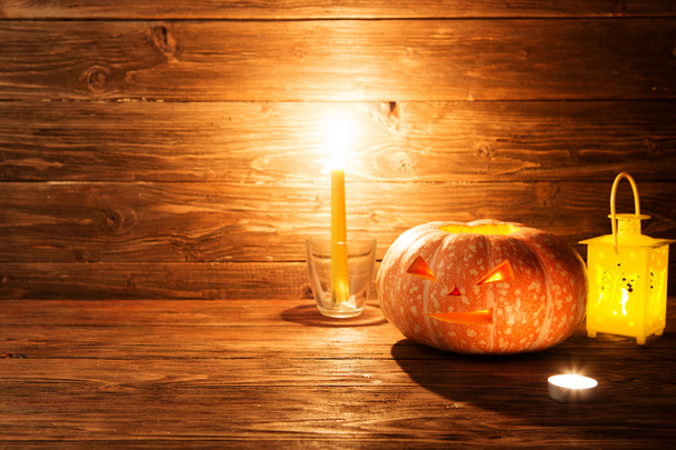 Halloween carved pumpkin and candle on wooden background - Fotó, kép