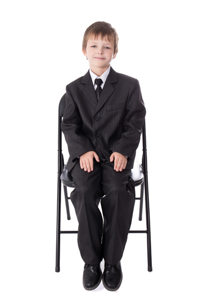 маленький мальчик в деловом костюме, сидя на офисный стул, изолированные на  - Фото, изображение