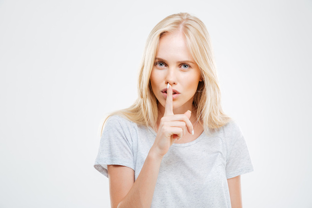 Pretty blonde woman showing finger over lips - Photo, Image