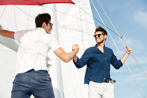 Two young handsome men greeting standing on the yacht - Foto, afbeelding