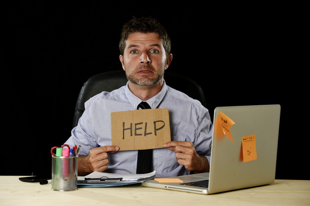 tired desperate businessman in stress working at office computer desk holding sign asking for help  - 写真・画像