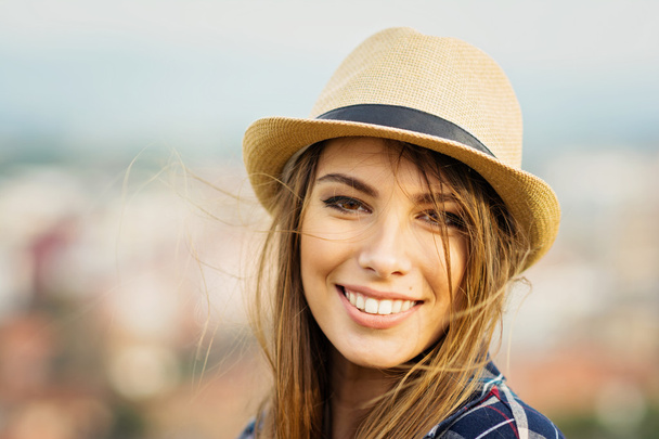 Closeup portrait of gorgeous blonde young woman in brown fedora on windy day - Foto, imagen
