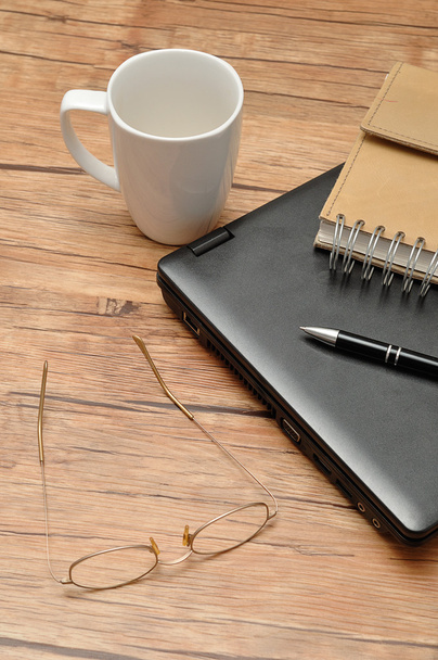 Laptop con un cuaderno de cuero, un bolígrafo y una taza blanca vacía
 - Foto, Imagen