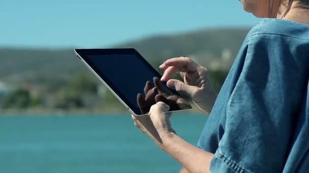 Крупним планом жінці за допомогою планшетного ПК на березі моря - Кадри, відео