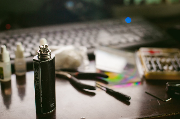 man prepares coil electronic cigarette smoking tasty vape juice. Device for the vaporization service. close up. heated coil - Foto, Imagen
