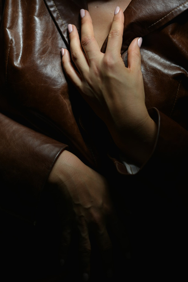 Τα χέρια της μια γυναίκα σε ένα καφέ δερμάτινο παλτό - Φωτογραφία, εικόνα