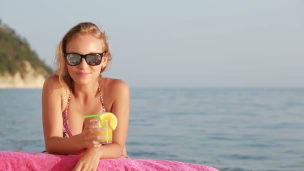 Girl in bikini drink juice through a straw. woman at the sea. - Imágenes, Vídeo