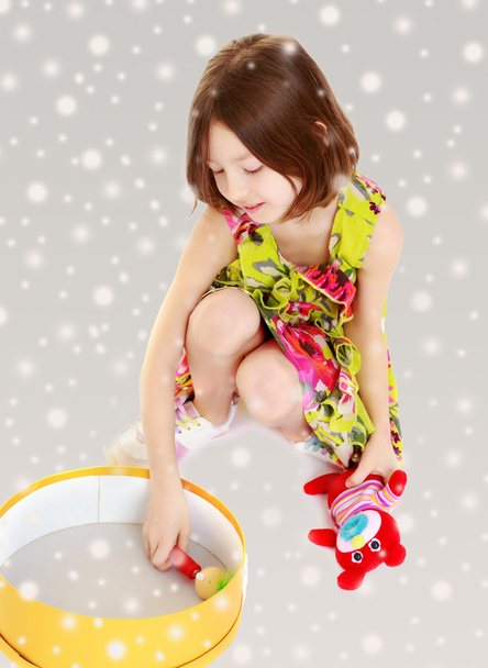 Little girl playing with a round box. - Zdjęcie, obraz
