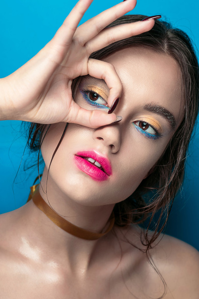 Beauty Girl Portrait with Vivid Makeup. Fashion Woman portrait close up on blue background. Bright Colors. Manicure Make up. Smoky eyes, long eyelashes. Rainbow Colors. Retouched shot - Foto, Imagem
