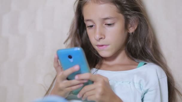 Girl child with a cell phone browses the Internet - Video, Çekim
