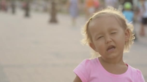 Roztomilá malá dívka hrát opice, mrknutí a vzduchu políbit ve veřejném parku - Záběry, video