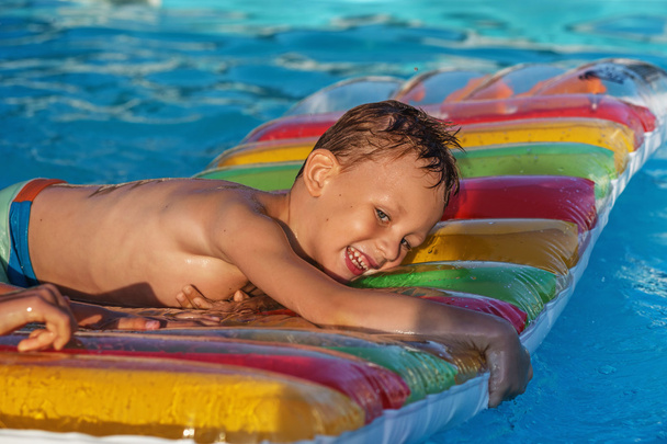 Niño feliz jugando en el agua azul de la piscina
. - Foto, imagen