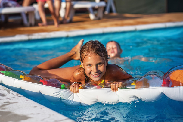 Szczęśliwe dzieci bawią się w błękitnej wodzie basenu. - Zdjęcie, obraz