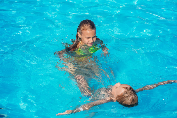Onnelliset lapset leikkivät uima-altaan sinisessä vedessä.
. - Valokuva, kuva