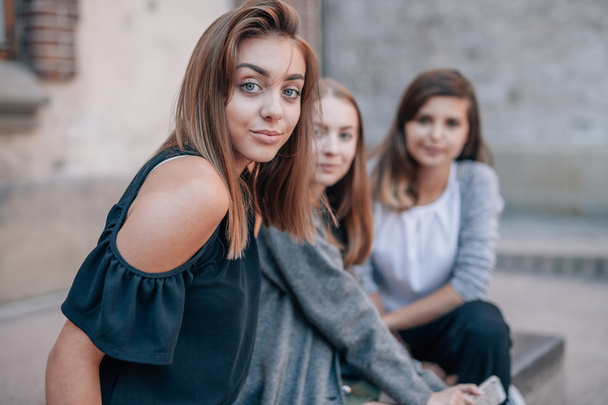 Three girls are sitting at streets stairs and posing to photo. C - Fotó, kép