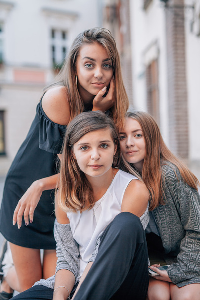 Three girls are sitting at streets stairs and posing to photo. C - Φωτογραφία, εικόνα