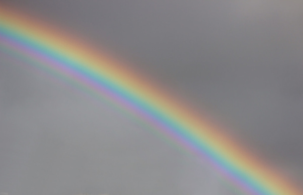 φωτεινά πολύχρωμα φαρδύ πολύχρωμο ουράνιο τόξο μετά την καταιγίδα στον γκρίζο ουρανό. - Φωτογραφία, εικόνα