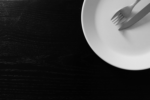 Empty white plate on black wooden table - Foto, Imagem