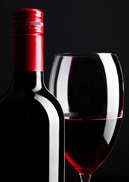 Red wine bottle and glass closeup on black - Foto, Bild