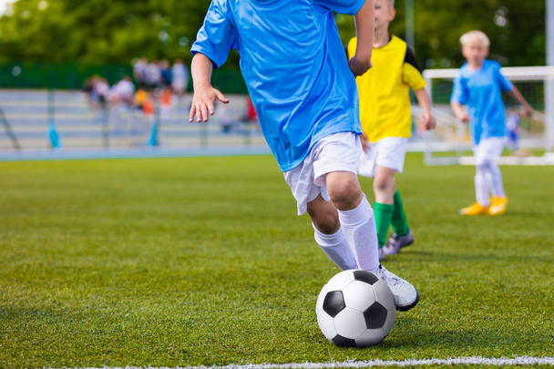 トレーニングとサッカー青年間サッカー チームで一致します。少年サッカーのゲームをプレイします。蹴るサッカー ボールを実行している選手間の競争。子供のためのサッカー大会のゲーム。スポーツの背景. - 写真・画像