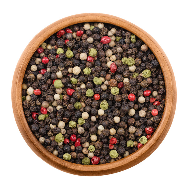 Mixed peppercorns in a wooden bowl over white - Photo, Image