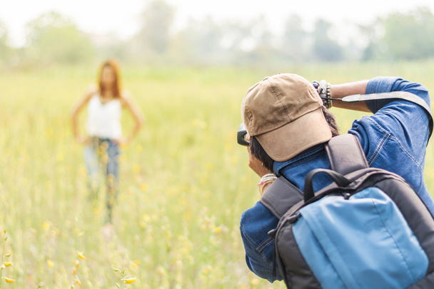 Man photographing young beautiful woman against in green field a - Фото, зображення